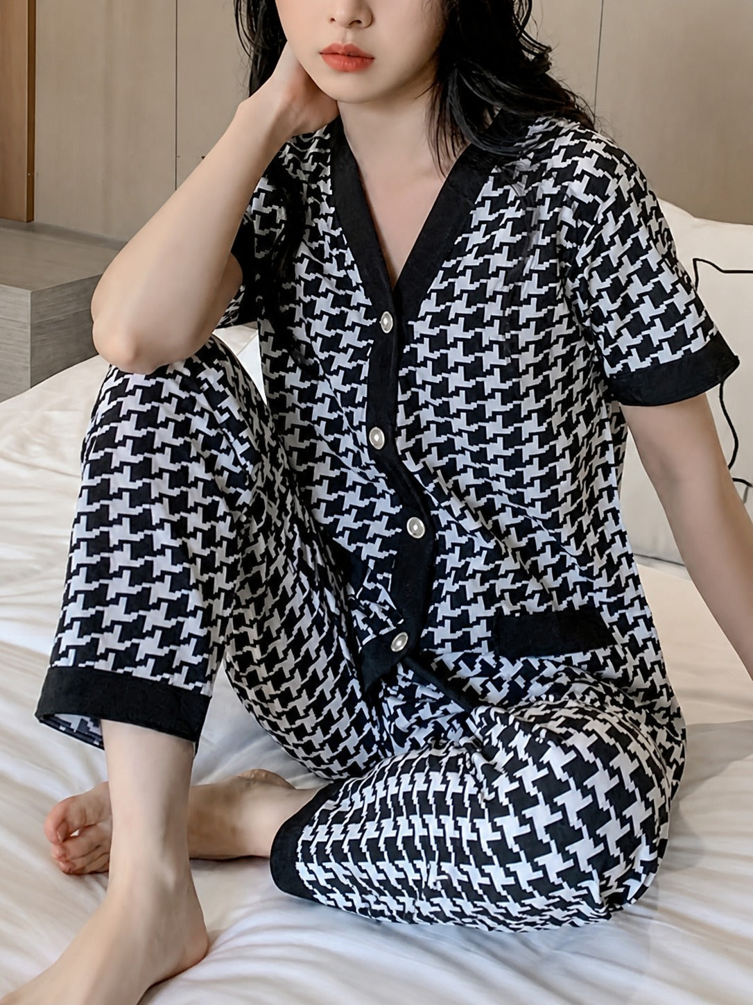 Person wearing a black and white patterned outfit in a bedroom setting