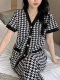 Person wearing a black and white patterned outfit sitting on a bed.