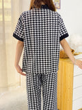 Person wearing a black and white houndstooth pattern outfit in a room.