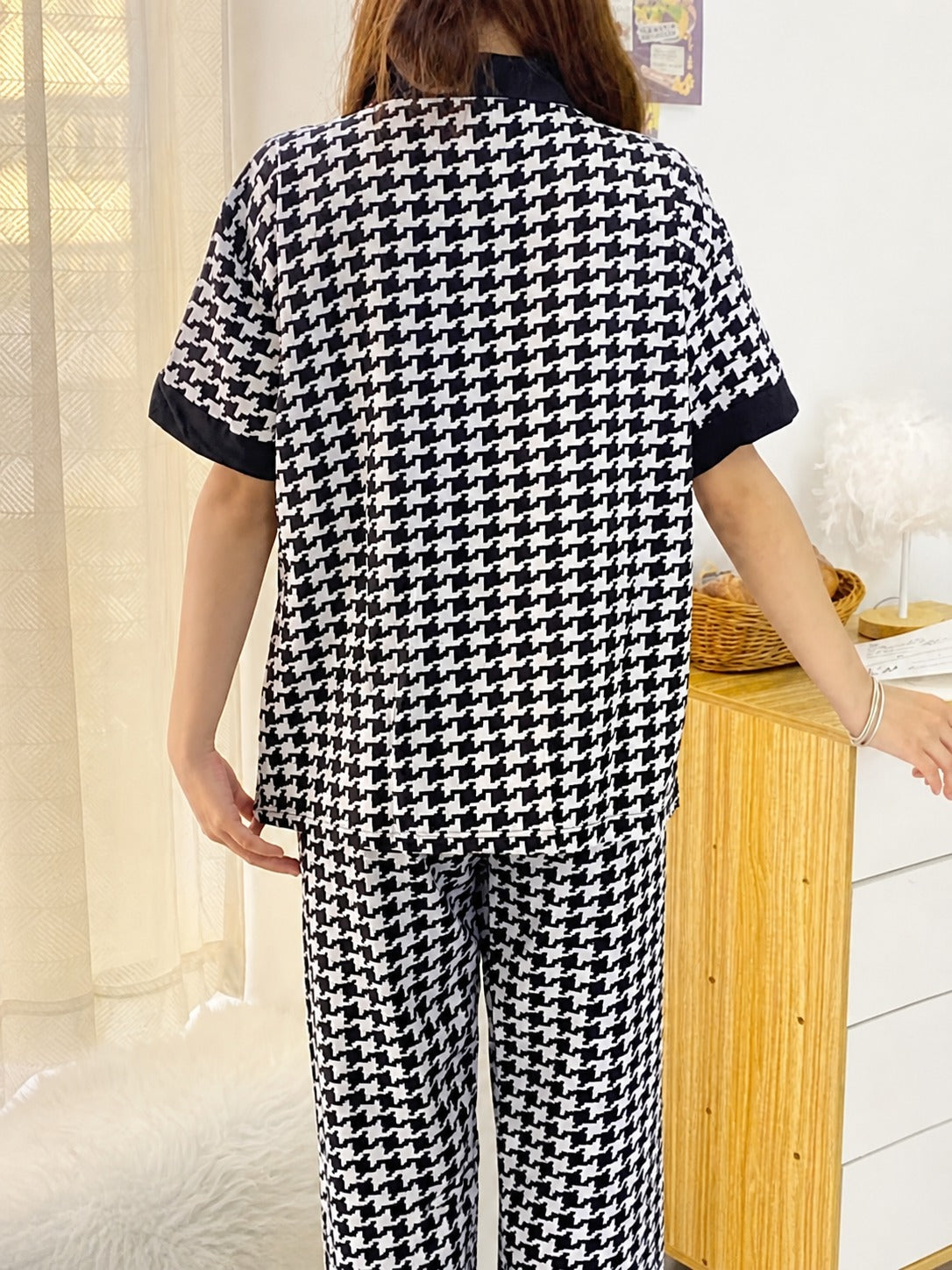 Person wearing a black and white houndstooth pattern outfit in a room.