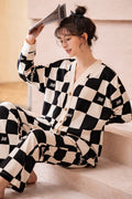 Woman wearing a black and white checkered outfit sitting on a light-colored floor.