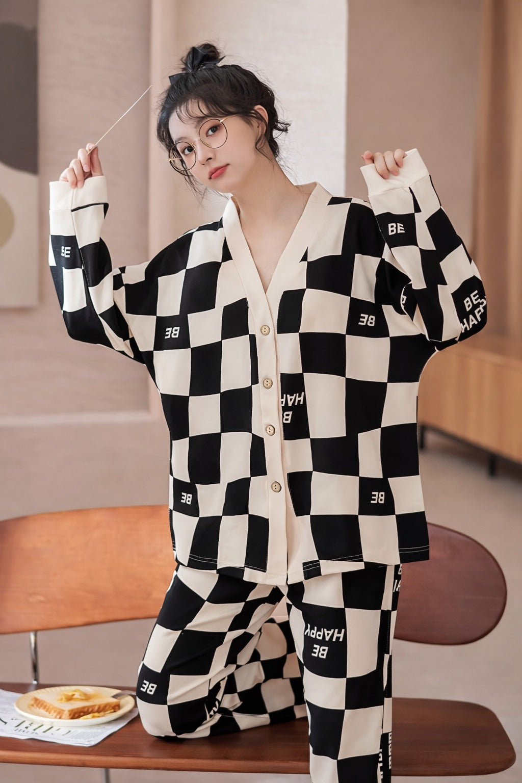 Person wearing a black and white checkered outfit with brand logos, sitting at a table.