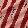 Close-up of pink fabric, maroon stripes and Success print